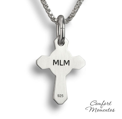 Back of small silver cross necklace with MLM engraved in black letters
