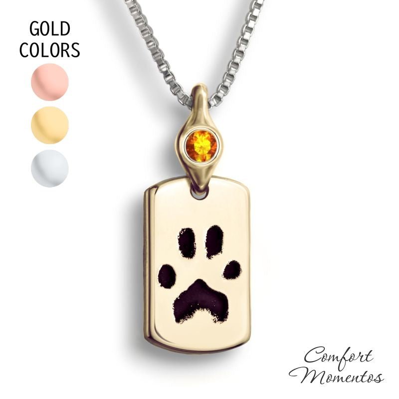Small gold dog tag necklace with black pawprint engraving, with a gemstone urn