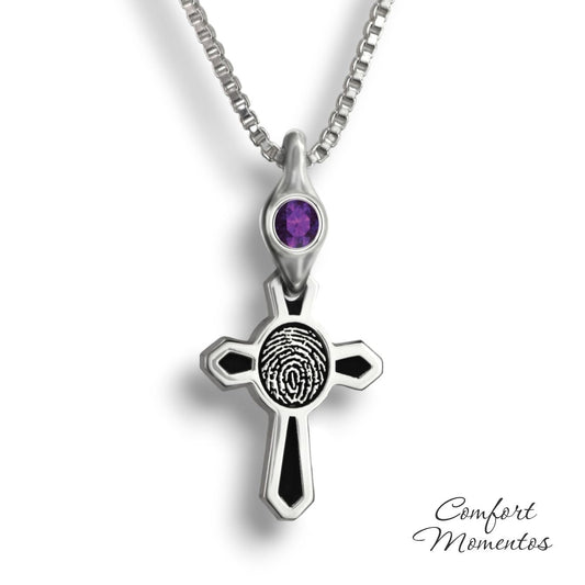 Small silver cross necklace with black fingerprint and recessed black areas, with a gemstone urn