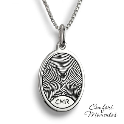 Silver oval necklace with a black fingerprint and initials engraved