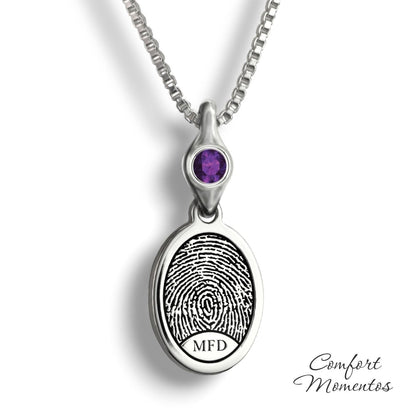 Small silver oval necklace with a black fingerprint and initials engraved, with a gemstone urn