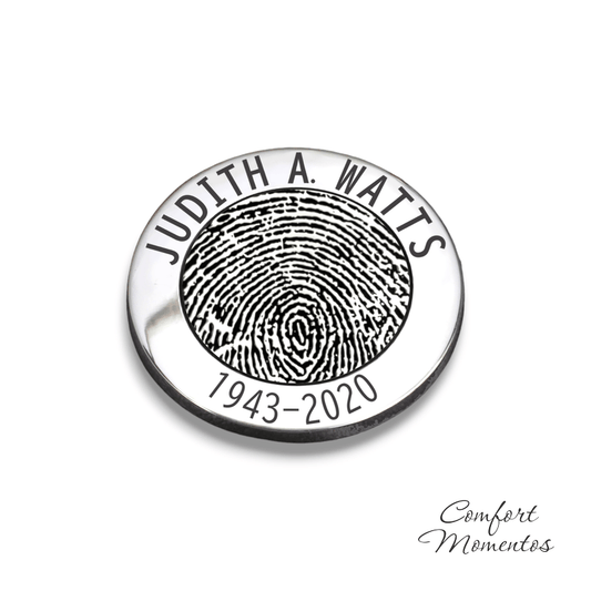 Round silver pocket coin or golf ball marker engraved with a black fingerprint and text